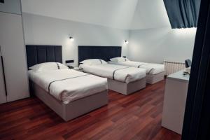 três camas num quarto com pisos de madeira em Green Hill em Almaty