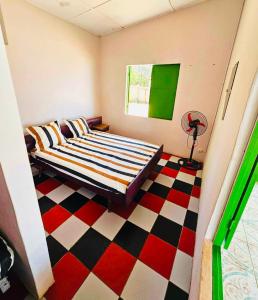 a bedroom with a bed and a checkered floor at Maison les pieds dans l'eau (Ramena) in Andjamen
