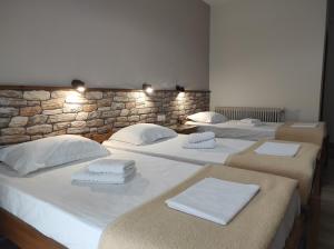 three beds in a room with a stone wall at Ενοικιαζόμενα Δωμάτια Ενιπεύς- Rooms Enipeas in Litochoro