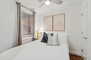 a white bedroom with a large white bed with pillows at Unique & Charming 2 Bedroom One Block to King St in Charleston