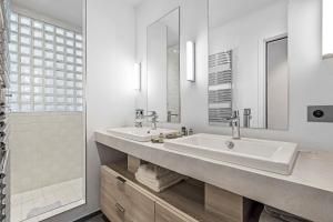 a white bathroom with two sinks and a shower at Maison Misericorde in Saint-Tropez