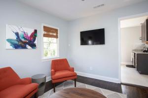 a living room with two chairs and a tv on a wall at Freshly Renovated 2 Bedroom Apt 1 Block to King in Charleston