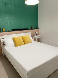 Una gran cama blanca con almohadas amarillas en una habitación. en Delia’s Apartments, en Acireale