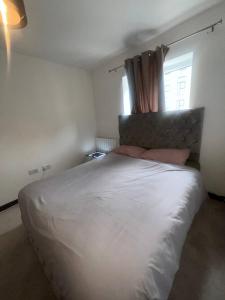 Schlafzimmer mit einem großen weißen Bett und einem Fenster in der Unterkunft NDO DARTFORD LUXX PRIVATE ENSUITE-ROOM in Dartford