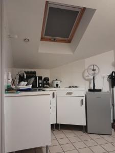 een keuken met witte kasten en een tv aan het plafond bij Appartement meublé à 30 minutes de Paris in Mantes-la-Jolie