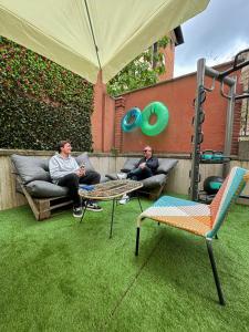 dos hombres sentados en sofás en un patio trasero con un paraguas en Free Hostels Roma, en Roma
