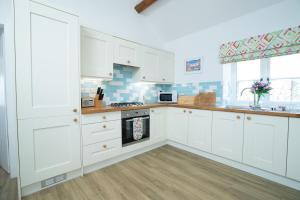 Una cocina con gabinetes blancos y un horno de estufa. en Bron Haul, en Newborough