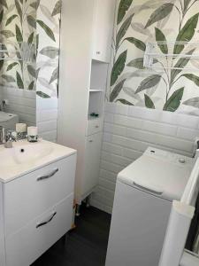 uma casa de banho branca com um lavatório e um WC em Le Ptit Duplex em Royan