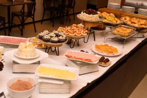 uma mesa cheia de diferentes tipos de bolos e doces em Gran Executive Hotel em Uberlândia