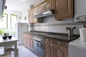 a kitchen with wooden cabinets and a white refrigerator at El clavelar del Sablón in Llanes