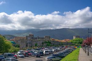 a parking lot full of cars in front of a castle at El clavelar del Sablón in Llanes