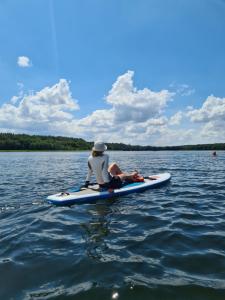 a person sitting on a paddle board in the water at Ferienwohnung Peetsch am See in Mirow +12 photos