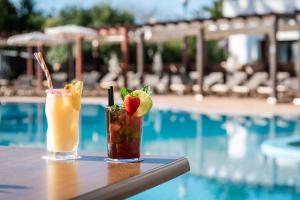 two cocktails sitting on a table next to a swimming pool at ALEGRIA Florida Park in Santa Susanna