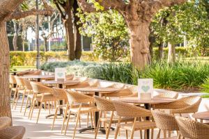 a row of tables with chairs and trees at ALEGRIA Florida Park in Santa Susanna