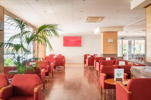 a waiting room with red chairs and plants at ALEGRIA Florida Park in Santa Susanna