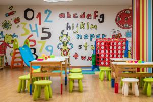 a classroom with tables and chairs and a wall with alphabet at ALEGRIA Florida Park in Santa Susanna