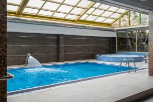 a swimming pool with a glass ceiling and a tub at ALEGRIA Florida Park in Santa Susanna