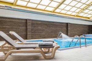 a swimming pool with two lounge chairs in front of it at ALEGRIA Florida Park in Santa Susanna