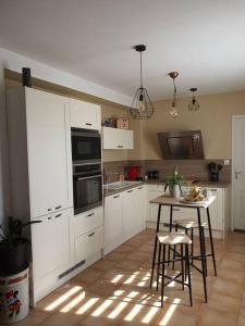 una cocina con armarios blancos y una mesa con sillas. en maison moderne, en Saint-Antonin-de-Sommaire