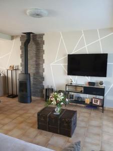 sala de estar con chimenea y TV de pantalla plana en maison moderne, en Saint-Antonin-de-Sommaire