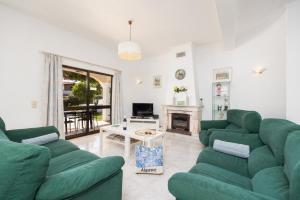 een woonkamer met 2 groene banken en een open haard bij Villa Cavaco in Vilamoura