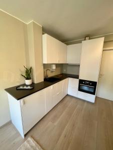 uma cozinha com armários brancos e um balcão preto em Modern apartment ONLY 5 minutes from City Centre em Bergen