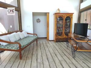 uma sala de estar com um sofá e uma televisão em Casa espetacular na praia Brava em Búzios