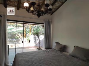 1 dormitorio con cama y ventana grande en Casa espetacular na praia Brava en Búzios