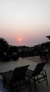 - deux chaises sur une terrasse avec un coucher de soleil en arrière-plan dans l'établissement Casa espetacular na praia Brava, à Búzios