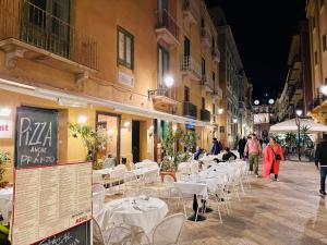 a group of tables and chairs in a street at night at Calvino Home in Trapani