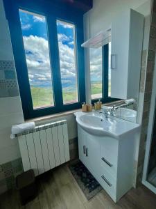 a bathroom with a white sink and two windows at Agriturismo Le Macine-Poggio Cono in Teramo