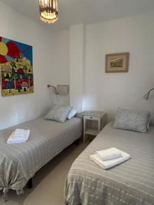 two beds in a room with a painting on the wall at Son de Mar 1 in Bolonia