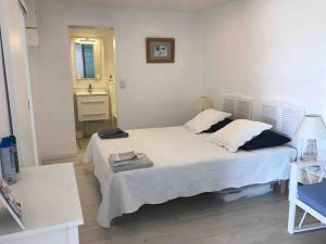 ein Schlafzimmer mit einem großen weißen Bett und einem Waschbecken in der Unterkunft Une fenêtre sur la mer in Le Gosier