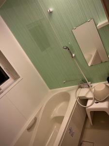 Villa美瑛・やさしい窓 في بيي: حمام مع حوض استحمام أبيض ومرحاض