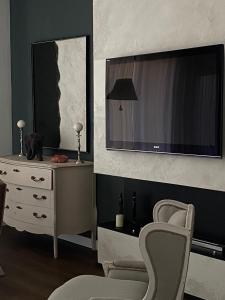 a living room with a tv and a chair and a dresser at 57 Design - Settimo Milanese, 2 camere da letto e 2 bagni in Settimo Milanese