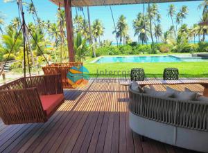 a wooden deck with chairs and a swimming pool at Villa Ramatuelle, Praia do Forte in Praia do Forte