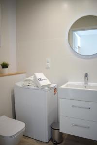 a white bathroom with a toilet and a sink at Apartos Seaside Garden Apartments I in Świnoujście