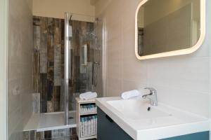 a bathroom with a sink and a shower at The Originals Boutique, Hôtel Roca-Fortis, Rochefort in Rochefort