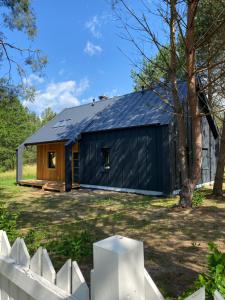 a black house with a black roof at Leśna Osada na Kaszubach - drewniane domy na wynajem in Bartoszylas