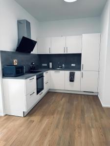 a kitchen with white cabinets and a wooden floor at Apartment ARTIC I Cityblick & Komfort in Nordhorn