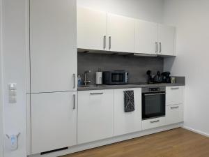 a white kitchen with white cabinets and a microwave at Apartment ARTIC III Ausblick & Citylage in Nordhorn
