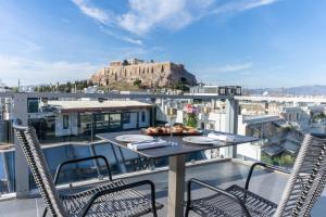 una mesa y sillas en un balcón con vistas en The Athens Gate Hotel en Atenas