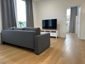 a living room with a couch and a flat screen tv at Apartment ARTIC III Ausblick & Citylage in Nordhorn +14 photos