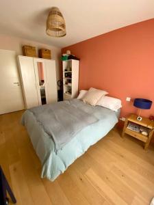 um quarto com uma cama e uma parede laranja em Appartement lumineux et calme em Bordeaux