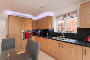 a kitchen with wooden cabinets and black counter tops at DBS Serviced Apartments - The Townhouse in Castle Donington