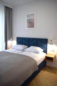 a bedroom with a large bed with a blue headboard at Apartos Seaside Garden Apartments I in Świnoujście