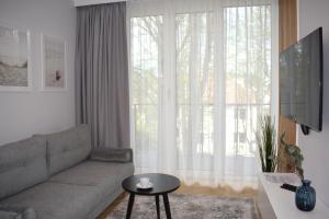 a living room with a couch and a large window at Apartos Seaside Garden Apartments I in Świnoujście