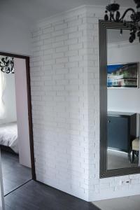 a mirror against a white brick wall next to a bedroom at Apartament Nad Zalewem in Zamość