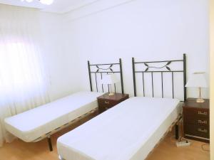 two beds in a room with two tables and lamps at Apartamento En Alcalá De Henares in Alcalá de Henares