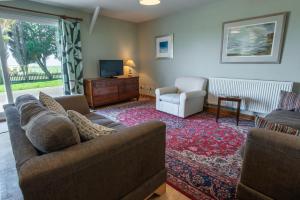 a living room with two couches and a tv at Ty Bach, Llanbedrog in Pwllheli